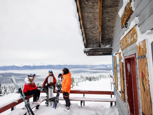 Three skiers/snowboarders on the deck at Hudson Bay Mountain Resort in Smithers, BC.